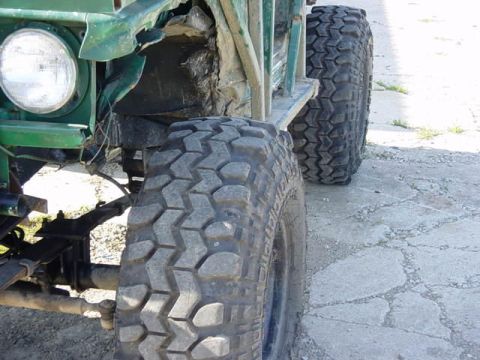 1992 Ford Bronco - Close-up view of the front tire and suspension of a modified off-road vehicle.