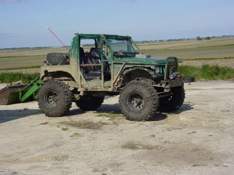 1992 Ford Bronco - Modified off-road vehicle with a front loader attachment parked on a dirt lot.