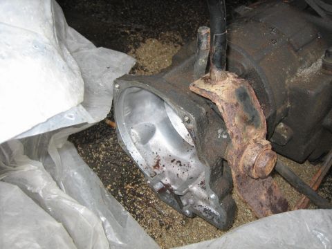 1994 Ford Bronco - A close-up view of a rusty bracket on a vehicle's transfer case component, partially covered by plastic.