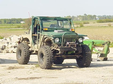 1992 Ford Bronco - This heavily modified off-road vehicle features a front loader attachment and appears to be in a rural setting.