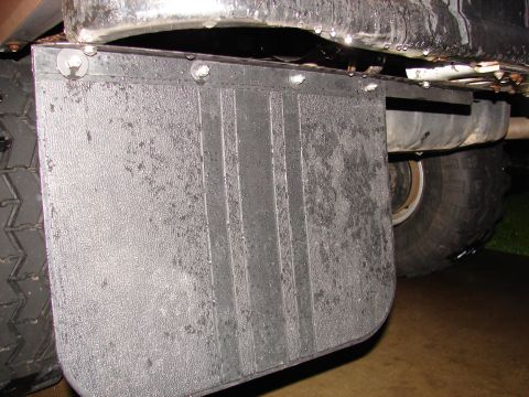 1996 Ford Bronco - Close-up view of a vehicle's mud flap and rear tire, showing some wear and tear.