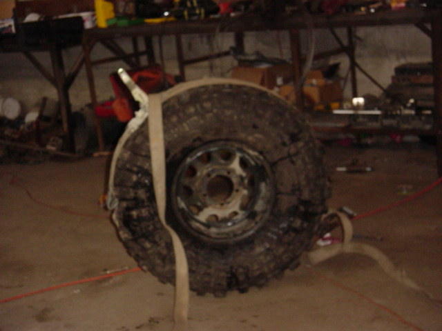Spare tire and wheel strapped down in a garage