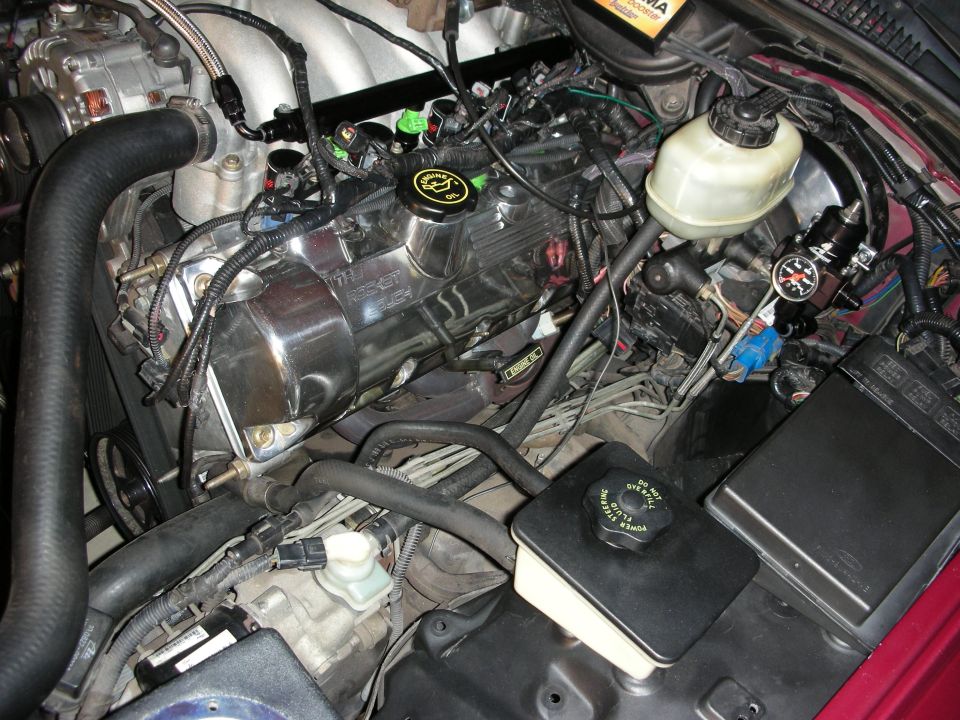 Engine bay with chrome valve covers, hoses, and wiring visible