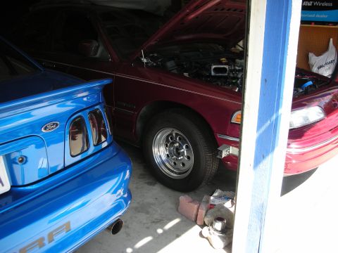 1992 Ford Crown Victoria - A maroon 1992 Ford Crown Victoria is parked in a garage with its hood open, alongside a blue vehicle.