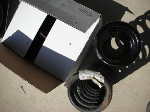 1992 Ford Crown Victoria - Two car springs sit on the ground next to an open cardboard box with text indicating they are for a '92 Ford Crown Victoria.
