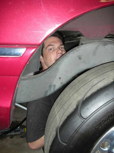 1992 Ford Crown Victoria - Mechanic works on the wheel well of a red vehicle.