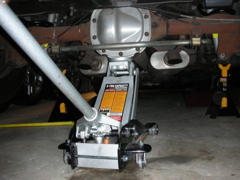 1992 Ford Crown Victoria - The rear axle and exhaust system of a vehicle are raised on a jack and jack stands for maintenance.