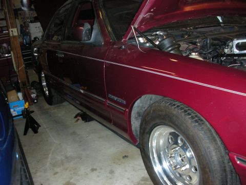 1992 Ford Crown Victoria - A maroon 1992 Ford Crown Victoria is shown in a garage with its hood up, revealing engine work.