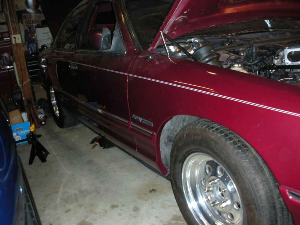 Maroon 1992 Ford Crown Victoria with hood open, showing engine components. Chrome wheels and pinstripes visible