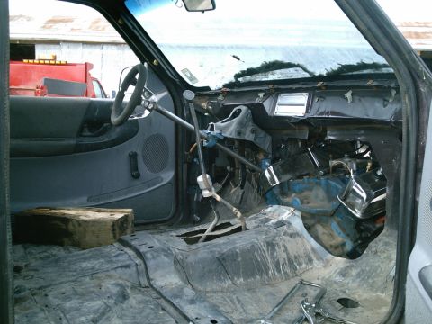 2001 Dodge 2500 - The interior of a truck cab shows significant modifications and a stripped-down appearance, with a block of wood on the floor.