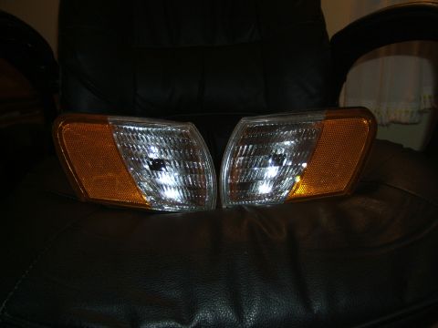 1998 Ford Taurus - Two front turn signal lights are displayed on a dark leather surface.