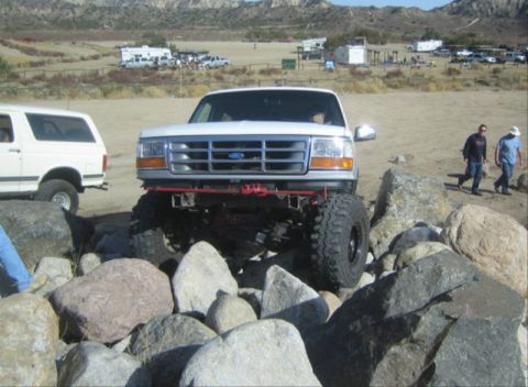 1996 Ford Bronco - A white Ford Bronco is parked on large rocks in a dry, outdoor area with mountains in the background.