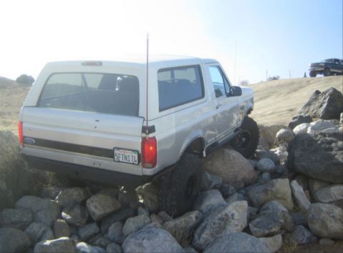 1996 Ford Bronco - A 1996 Ford Bronco navigates a challenging rocky path, with another vehicle visible in the background.