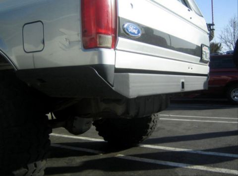 1996 Ford Bronco - Close-up of the rear bumper and tire of a Ford Bronco, with another vehicle visible in the background.