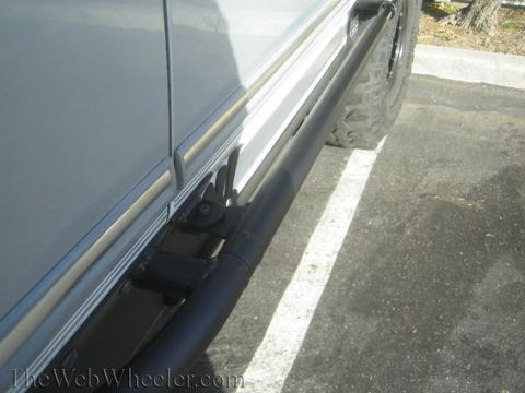 1996 Ford Bronco - A close-up view of a vehicle's side panel and a large tire, equipped with a black rock slider.
