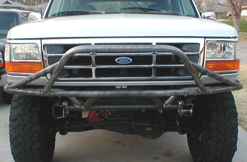 White lifted Ford with bare steel tube prerunner front bumper and chrome grille
