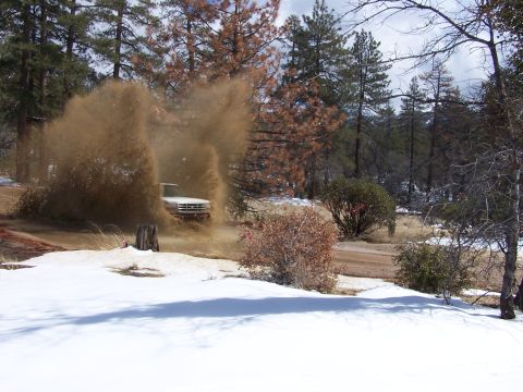 1996 Ford Bronco - A white pickup truck powers through a muddy patch on a snowy road, creating a large spray.