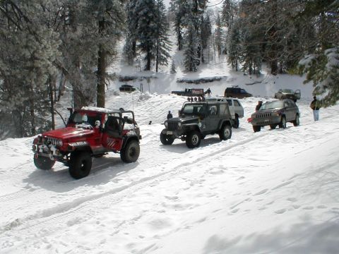 1996 Ford Bronco - Several off-road vehicles navigate a snowy mountain pass.