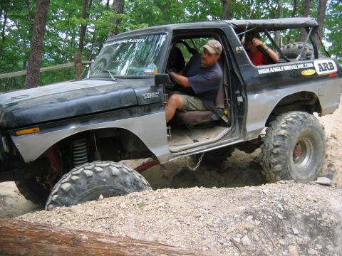 1992 Ford Mustang - A lifted Ford Bronco navigates a challenging off-road obstacle with a driver and passenger inside.
