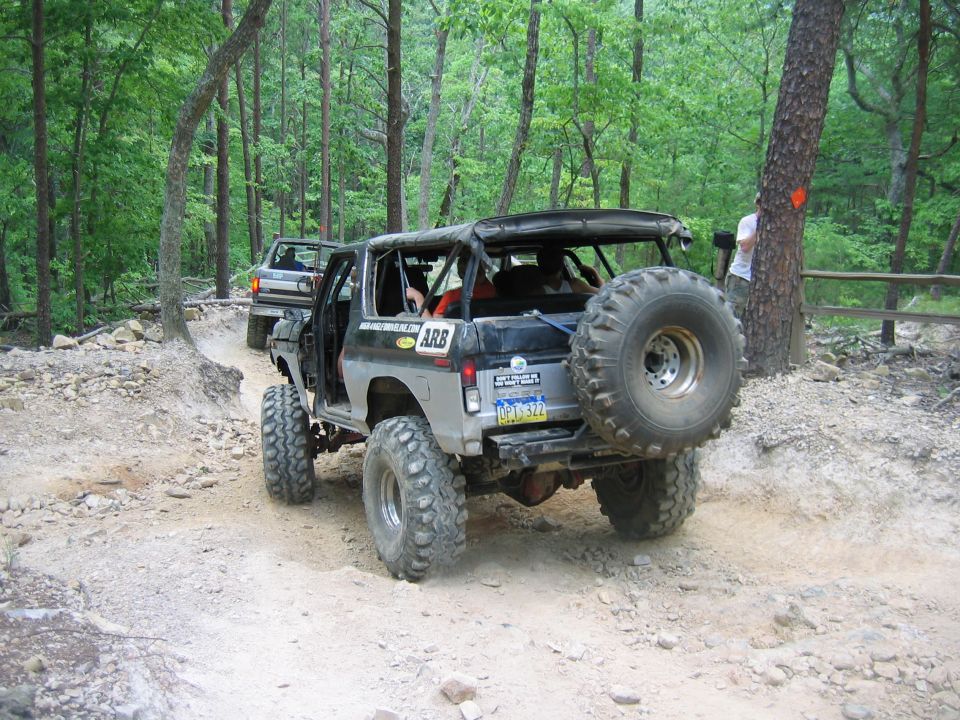 Off-road vehicle with spare tire on back, driving on dirt path