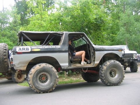 1992 Ford Mustang - Modified Ford Bronco with off-road tires and a spare tire on the back, parked next to another vehicle.