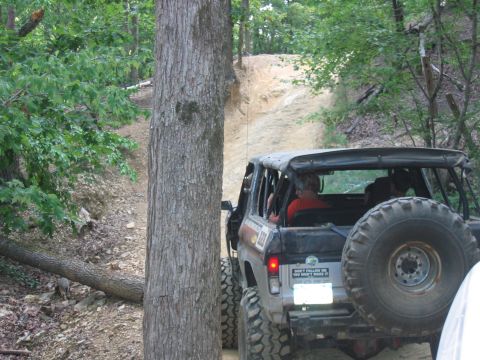 1992 Ford Mustang - An off-road vehicle navigates a steep dirt trail, its spare tire mounted prominently on the back.