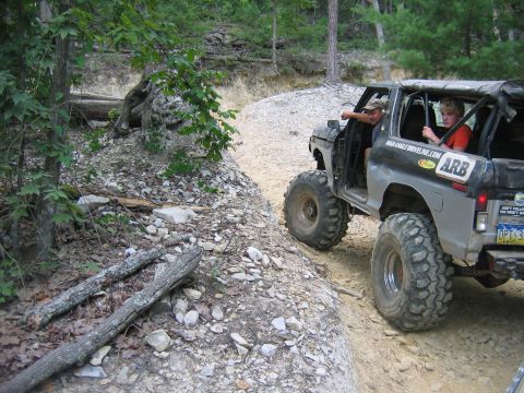 1992 Ford Mustang - Modified Ford Bronco navigating a challenging off-road trail with two occupants.