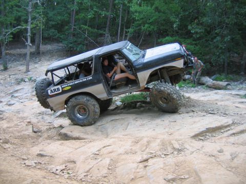 1992 Ford Mustang - Modified Ford Bronco tackling rough terrain off-road. Features large tires and a roll cage.