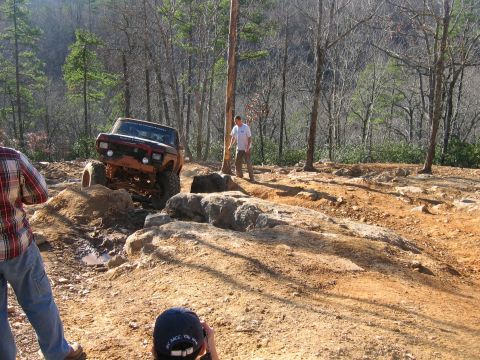 1992 Ford Mustang - An off-road vehicle navigates a challenging rocky terrain on a sunny day.