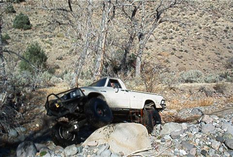 1986 Ford Bronco - A modified pickup truck navigates a rocky off-road course, its suspension and tire grip.