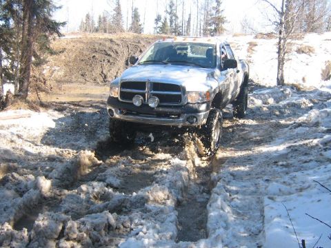 1995 Ford Bronco - A Dodge Ram pickup truck navigates a challenging snowy and muddy terrain.