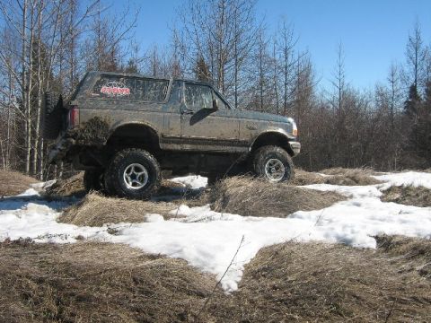 1995 Ford Bronco - 1995 Ford Bronco navigating a snowy, muddy off-road trail.