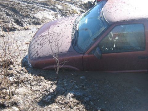 1995 Ford Bronco - This red SUV appears to be a 1998 Chevrolet S-10 Blazer, deeply stuck in a muddy ditch.