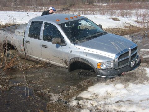 1995 Ford Bronco - Silver Dodge Ram pickup truck stuck in mud and snow, with a person on the bed.