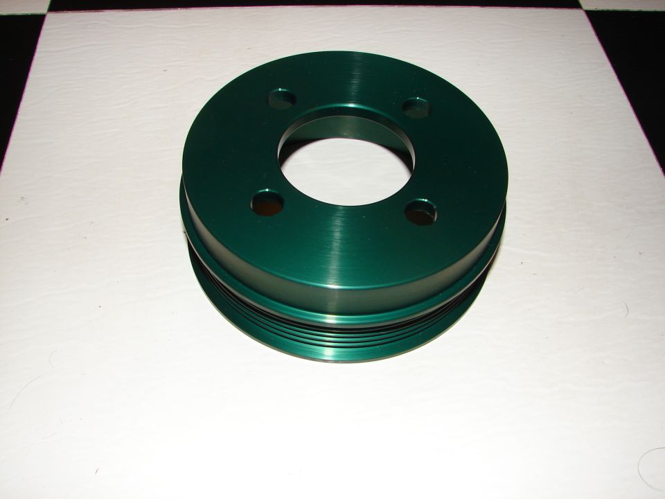Green pulley with four bolt holes and grooved circumference on a white surface