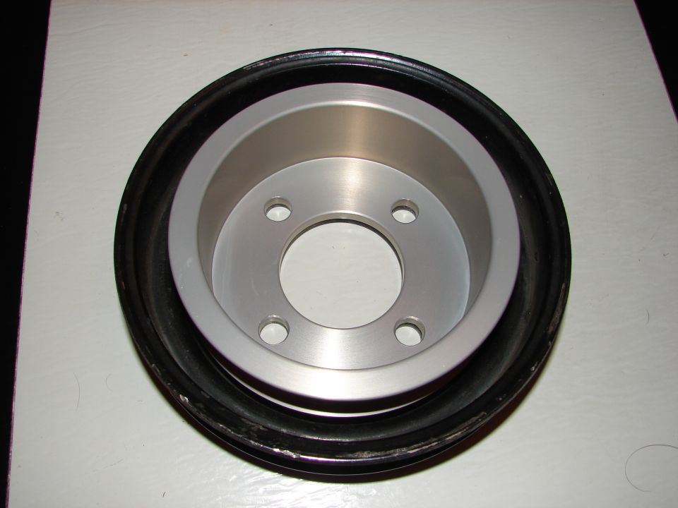 Crankshaft pulley with a black rubber ring and a silver metal hub with four bolt holes