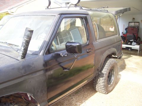 1989 Ford Bronco II - A black 1989 Ford Bronco II is parked in a garage with off-road modifications.