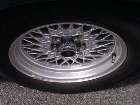 2001 Ford Crown Victoria - A close-up view of a vehicle's tire and a detailed silver wire wheel with a center cap.