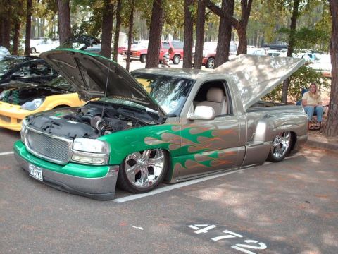 1990 Ford F-150 - This customized pickup truck features flame graphics and a lowered stance, parked outdoors.
