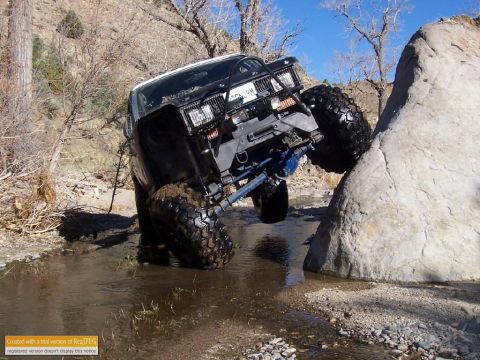 1986 Ford Bronco - A modified off-road vehicle navigates a challenging rocky stream bed, demonstrating its off-road capabilities.