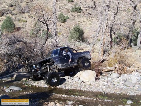 1986 Ford Bronco - A heavily modified Ford Bronco navigates a challenging off-road course through a stream.