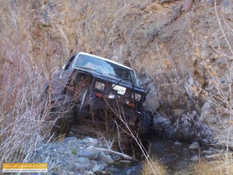 1986 Ford Bronco - Off-road vehicle navigates a challenging rocky terrain with a creek running through it.