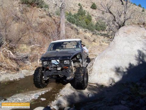 1986 Ford Bronco - Modified 1986 Ford Bronco tackling a challenging off-road trail with rocky obstacles.