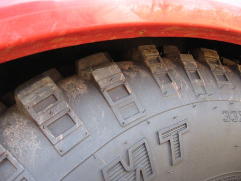 1995 Ford F-150 - A close-up view of an aggressive tire tread pattern, with a red fender flare visible overhead.