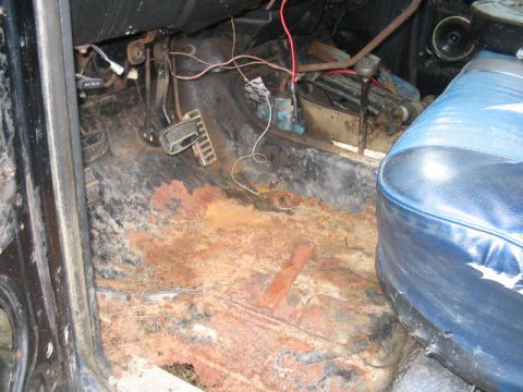 1979 Ford Bronco - The interior floor of a vehicle shows significant rust damage and is covered in debris.