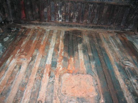 1979 Ford Bronco - The ribbed metal floor of a truck bed shows significant rust and wear.