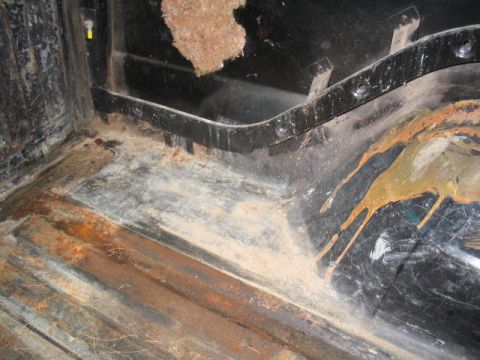 1979 Ford Bronco - The interior cargo area shows significant rust and dirt, with visible metal floor panels and black interior trim.