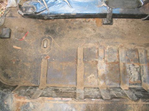 1979 Ford Bronco - The interior floor of a vehicle shows signs of wear and dirt, with blue seat upholstery visible at the top.