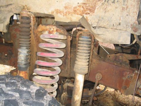 1979 Ford Bronco - The image shows heavily rusted suspension components of a vehicle, including coil springs and shock absorbers, with a tire in the foregroun…