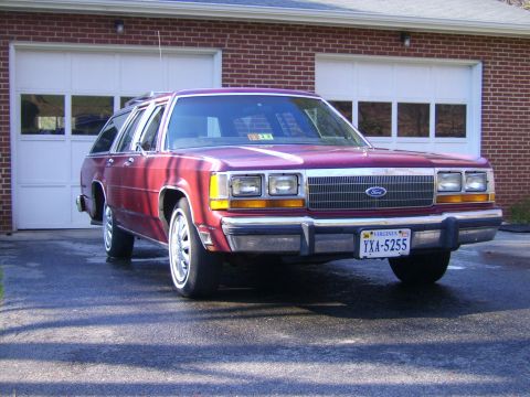 1982 Ford LTD Crown Victoria - A maroon station wagon is parked in front of a garage, its front end angled towards the camera.